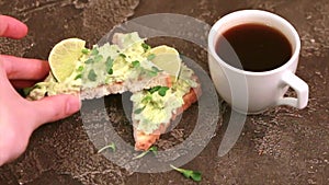 Toasts with avocado pate, fresh microgreen and cup of coffee on dark concrete background
