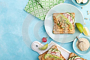 Toasts with chickpea hummus, avocado, fresh radish, cucumber, sesame seeds and flaxseed sprouts. Diet breakfast. Delicious and hea