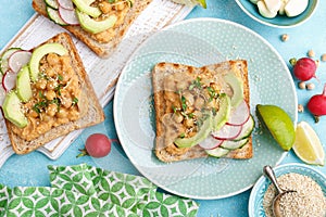 Toasts with chickpea hummus, avocado, fresh radish, cucumber, sesame seeds and flaxseed sprouts. Diet breakfast. Delicious and hea