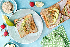 Toasts with chickpea hummus, avocado, fresh radish, cucumber, sesame seeds and flaxseed sprouts. Diet breakfast. Delicious and hea