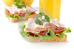 Toasts with cold cuts for breakfast with orange juice on white