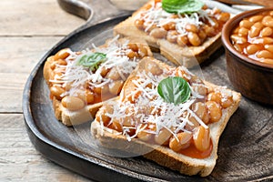 Toasts with delicious canned beans on wooden table, closeup