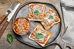 Toasts with delicious canned beans on wooden table, flat lay