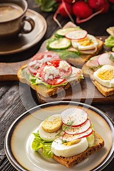 Toasts with eggs, cheese, ham, radish, cucumbers and tomatoes , breakfast ida.