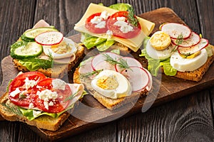 Toasts with eggs, cheese, ham, radish, cucumbers and tomatoes , breakfast idea