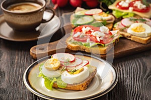 Toasts with eggs, cheese, ham, radish, cucumbers and tomatoes , breakfast idea