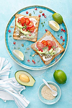 Toasts with feta cheese, tomatoes, avocado, pomegranate, pumpkin seeds and flaxseed sprouts. Diet breakfast. Delicious and healthy