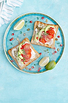 Toasts with feta cheese, tomatoes, avocado, pomegranate, pumpkin seeds and flaxseed sprouts. Diet breakfast. Delicious and healthy