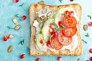 Toasts with feta cheese, tomatoes, avocado, pomegranate, pumpkin seeds and flaxseed sprouts. Diet breakfast. Delicious and healthy