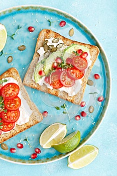 Toasts with feta cheese, tomatoes, avocado, pomegranate, pumpkin seeds and flaxseed sprouts. Diet breakfast. Delicious and healthy