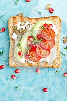 Toasts with feta cheese, tomatoes, avocado, pomegranate, pumpkin seeds and flaxseed sprouts. Diet breakfast. Delicious and healthy