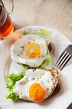 Toasts with fried eggs near hot tea