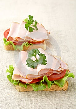 Toasts with lettuce,cold cuts on linen tablecloth