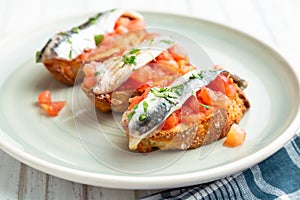 Toasts of marinated anchovies with fresh tomato and olive oil