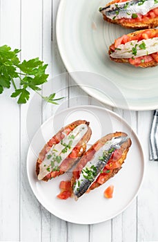 Toasts of marinated anchovies with fresh tomato and olive oil