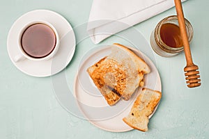 Toasts on a plate, a spoon on a jar of honey and coffee in a cup