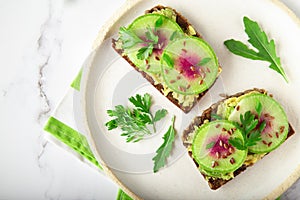 Toasts with watemelon radish, avocado and flex seeds