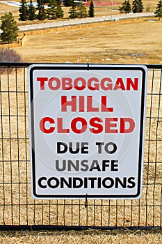 Toboggan hill closed sign posted in a public park once all the snow has melted