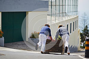 Toboggan riders moving cane sledge downhill on the streets of Funchal, Madeira island