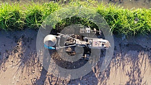 tod down view to undefined Indonesian Farmer working with tractor on a ricefield. Aerial drone shot photo