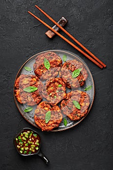 Tod Mun Pla or Thai Fish Cakes on black plate on dark slate table top. Traditional Thailand cuisine dish
