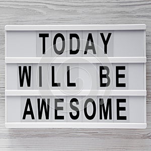 `Today will be awesome` words on lightbox over white wooden surface, top view. Overhead, flat lay, from above