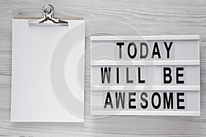 `Today will be awesome` words on modern board, noticepad over white wooden background, overhead view.