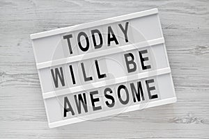 `Today will be awesome` words on modern board over white wooden surface, overhead view.