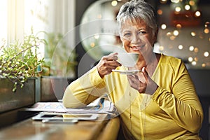 Todays mood is sponsored by coffee. Portrait of a mature woman enjoying a warm beverage at a coffee shop.