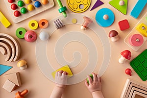 Toddler activity for motor and sensory development. Baby hands with colorful wooden toys on light table top view