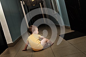 Toddler baby alone in a dark corridor. A lonely child boy sits in the dark