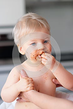 Toddler baby boy child eating fruit with dirty messy face