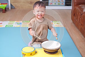 Toddler baby boy child hold sticks & plays a musical instrument drum