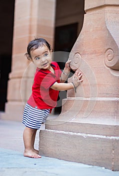 toddler baby boy cute facial expression standing with wall support in casual appearance at outdoor