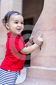 toddler baby boy cute facial expression standing with wall support in casual appearance at outdoor