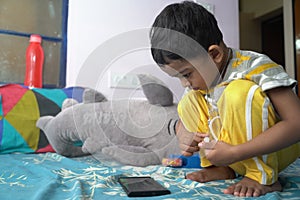 a toddler baby boy engaged in watching and exploring mobile phone.Screen time addiction concept image