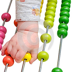 Toddler baby boy plays with his hands with colorful abacus on the floor