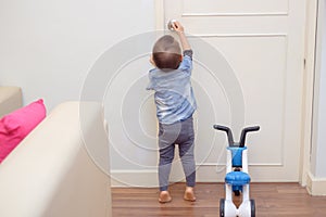 toddler baby boy standing on tiptoes at home