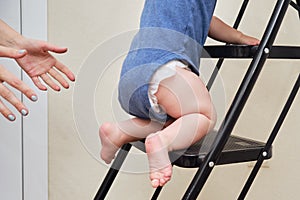 Toddler baby climbs on the steps ladder. Child boy climbs up the stairs