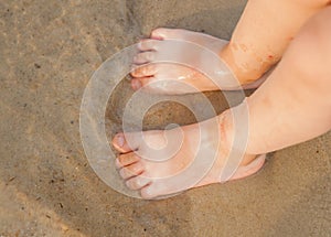 Toddler baby doing his first steps on the beach. Bare feet baby staying on the sand near the bank in sunny day. Summertime holiday