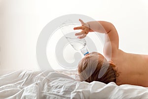 Toddler baby drink water from blue plastic bottle. Sitting on white background. Copy space