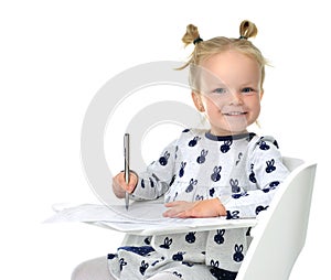 Toddler baby girl learning how to write on a paper book with pen