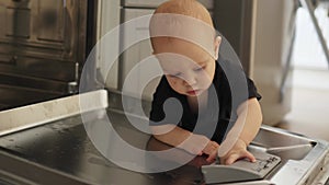 toddler baby kid black shirt playing opened dishwasher touching plastic bin