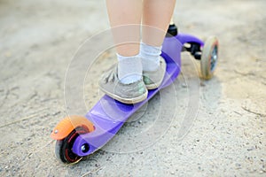 Toddler baby learning to ride kick scooter. Child feet close up. Sport lifestyle and leisure for kids