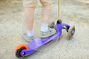 Toddler baby learning to ride kick scooter. Child feet close up. Sport lifestyle and leisure for kids