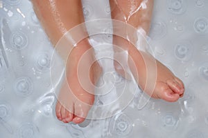 Toddler baby legs on a non-slip mat in the bathtub. Child boy foots was