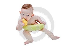 Toddler baby plays with a yellow duck toy while bathing, isolated on a