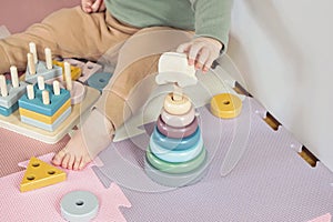 Toddler baby sitting on carpet playing with colorful wooden stacking toy