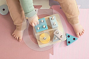 Toddler baby sitting on carpet playing with colorful wooden stacking toy