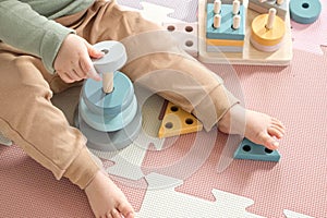 Toddler baby sitting on carpet playing with colorful wooden stacking toy